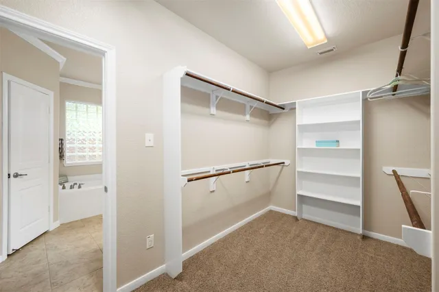 an empty room with chandelier fan and closet area