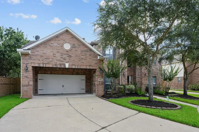 a front view of a house with a garden and trees