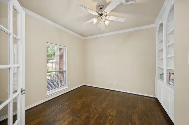 an empty room with wooden floor chandelier fan and windows