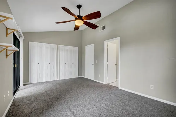 a view of an empty room with a ceiling fan and window
