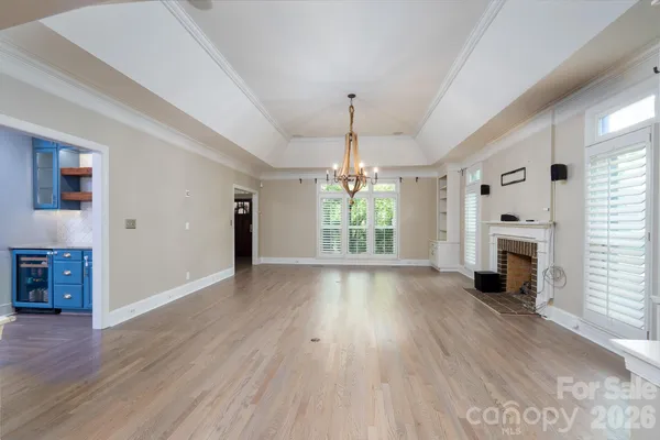 an empty room with wooden floor fireplace and windows
