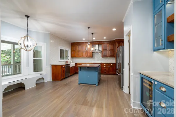 a large kitchen with a large center island wooden floor and stainless steel appliances