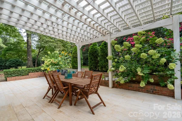 a patio with table and chairs and potted plants