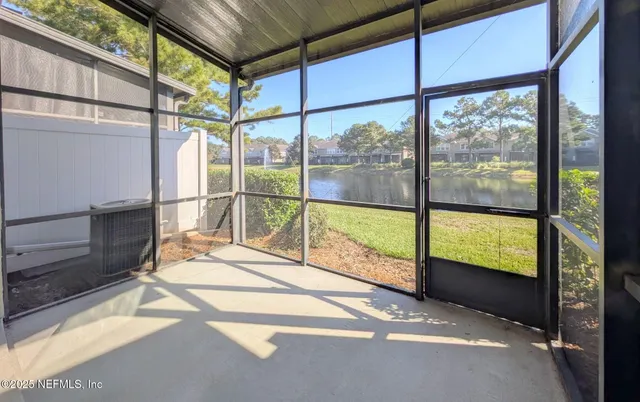 a view of an empty room with wooden floor and windows