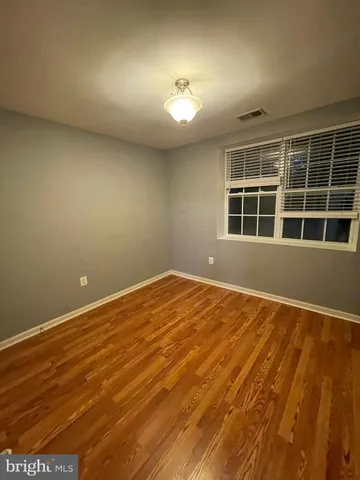a view of an empty room with wooden floor and windows