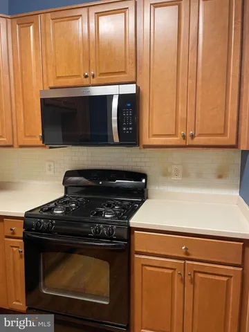 a kitchen with stainless steel appliances a sink a stove a refrigerator cabinets and a dining table