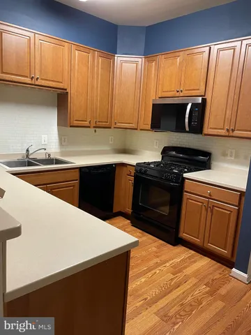 a kitchen with stainless steel appliances kitchen island granite countertop a refrigerator a sink dishwasher a stove and a oven with wooden floor