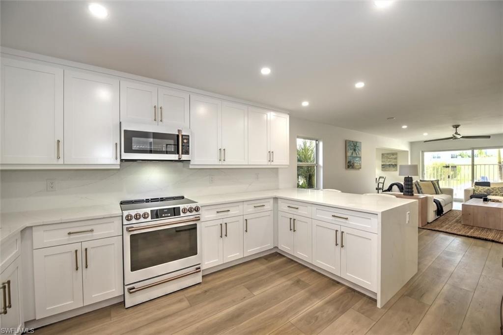 a open white kitchen with a white stove top oven and white cabinets