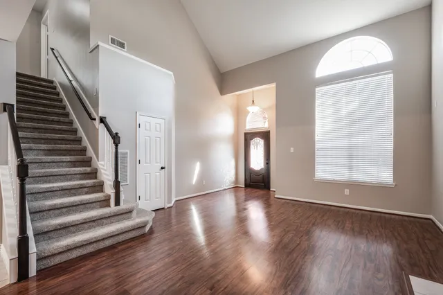 a view of an empty room with wooden floor and fan