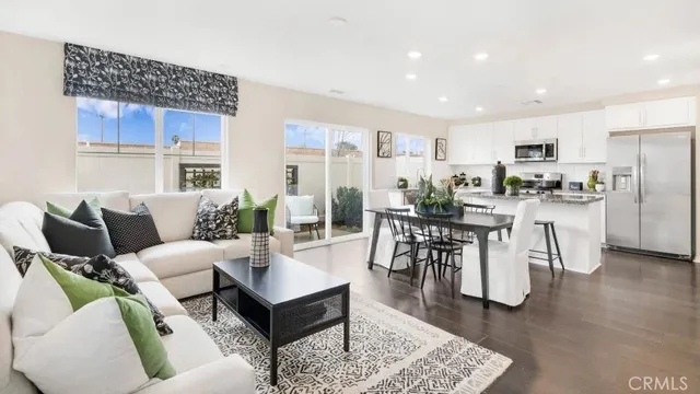 a living room with furniture a wooden floor and kitchen view