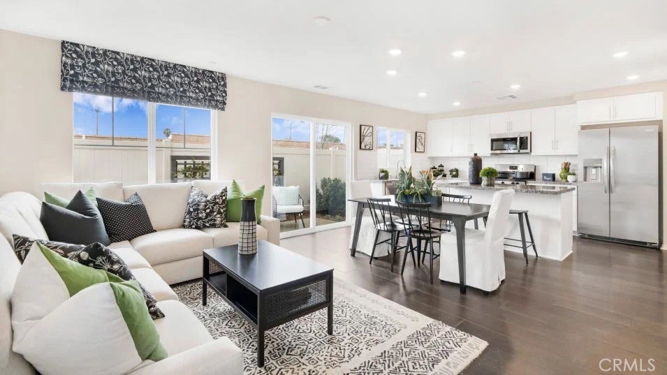 a living room with furniture a wooden floor and kitchen view