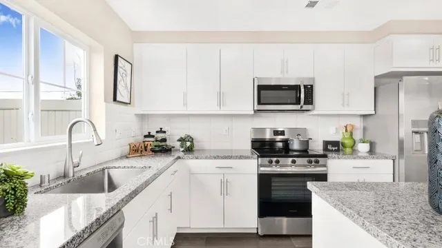 a kitchen with granite countertop a sink a stove and microwave
