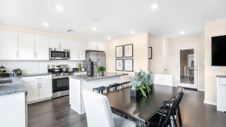 7464 Fig Grv Lane Riverside, CA 92507 - Photo 4 of 17 a kitchen with stainless steel appliances granite countertop a stove top oven a refrigerator a sink and a dining table with wooden floor