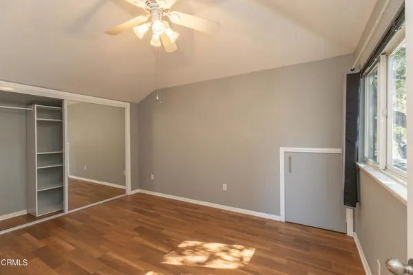 a view of empty room with wooden floor and fan