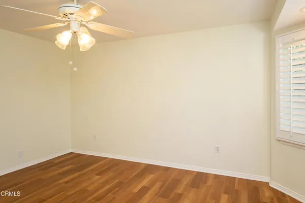 an empty room with a chandelier fan and windows