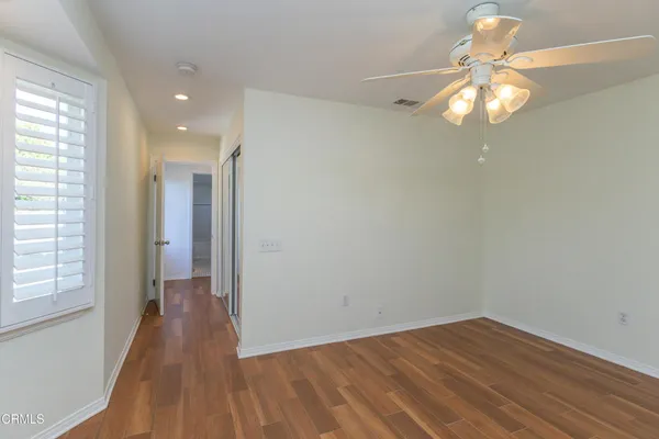 a view of empty room with wooden floor and fan