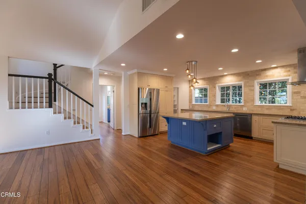 a living room with wooden floors and kitchen view