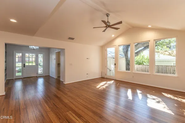 a view of an empty room with wooden floor and a window
