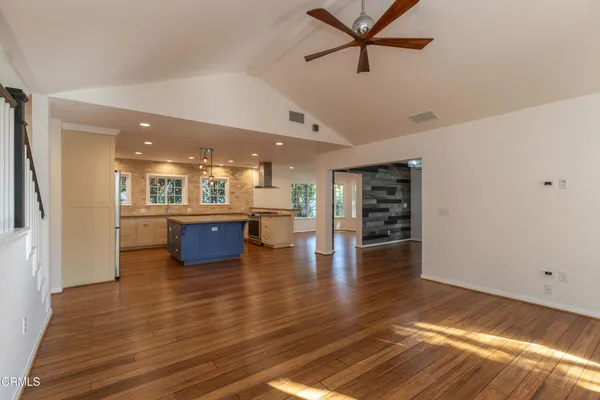 a living room with stainless steel appliances furniture and a kitchen view
