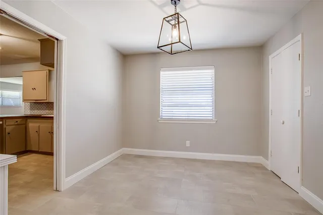 a view of empty room with a window and kitchen view