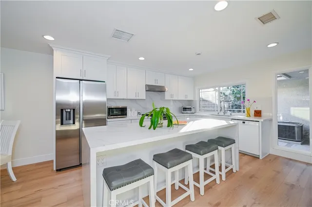 a kitchen with white cabinets and window
