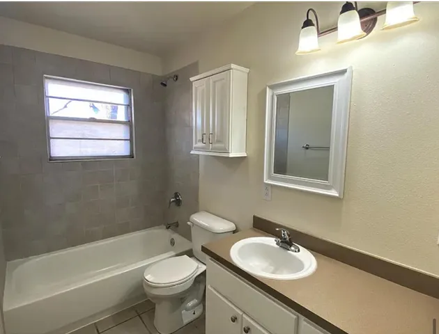 a bathroom with a granite countertop toilet a sink a mirror and bathtub
