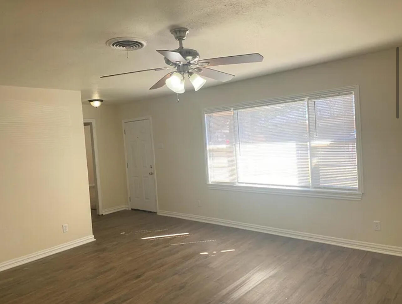 4908 43rd Street Lubbock, TX 79414 - Photo 3 of 18 an empty room with wooden floor fan and windows