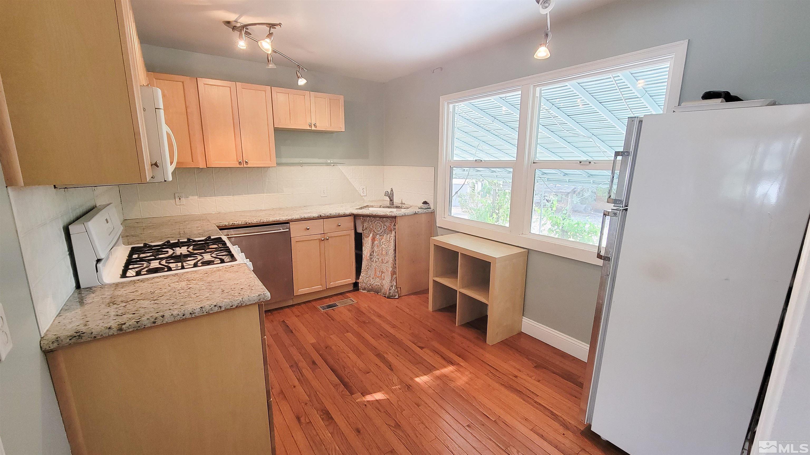 240 Bisby Street Reno, NV 89512 - Photo 5 of 27 a kitchen with granite countertop a refrigerator and a stove top oven
