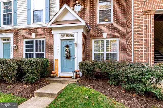a view of a brick house with plants and many windows