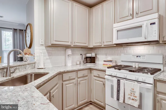 a kitchen with granite countertop white cabinets and a stove top oven