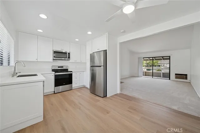 a kitchen with a refrigerator a stove top oven a sink and dishwasher with wooden floor