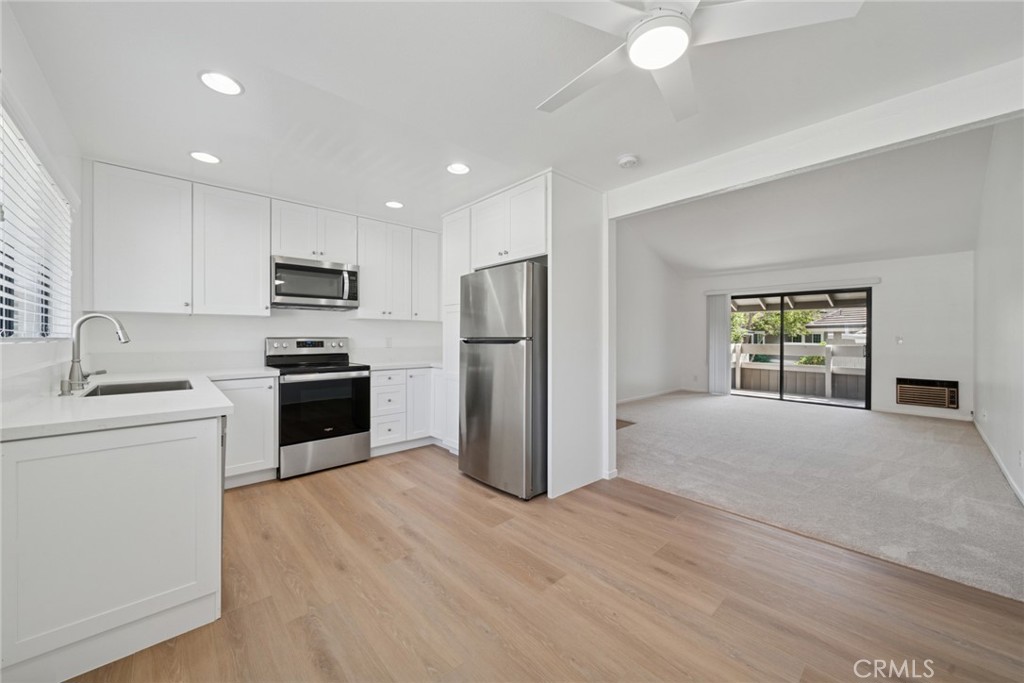 82 Streamwood Irvine, CA 92620 - Photo 4 of 26 a kitchen with a refrigerator a stove top oven a sink and dishwasher with wooden floor