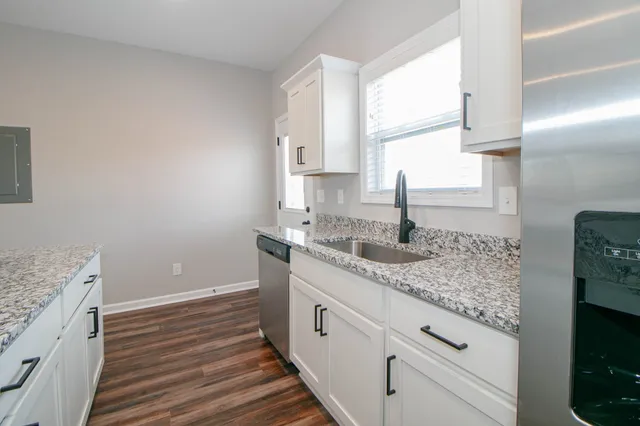 a kitchen with granite countertop white cabinets and a sink