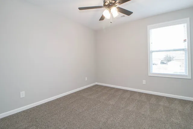 an empty room with a window and a fan