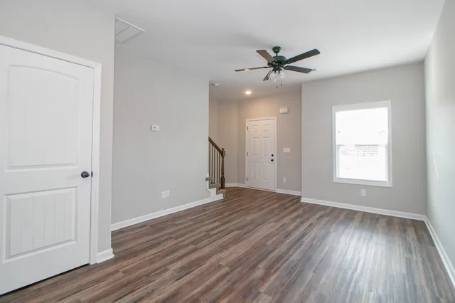 an empty room with wooden floor a ceiling fan and windows
