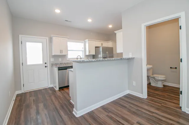 a kitchen with a sink a stove cabinets and wooden floor
