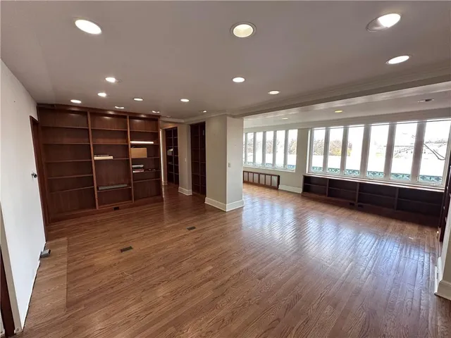 a view of an empty room with wooden floor and windows