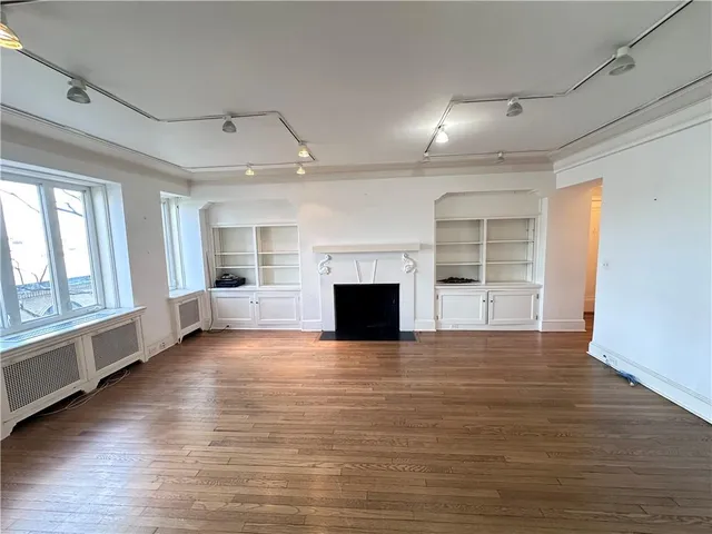 an empty room with wooden floor fireplace and windows