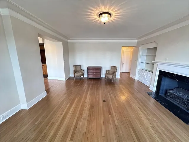 an empty room with wooden floor a fireplace and windows
