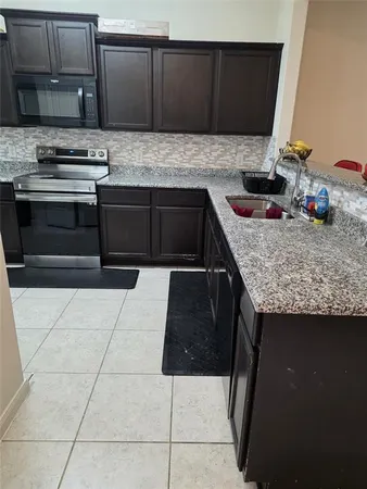 a kitchen with stainless steel appliances granite countertop a stove a sink and a microwave