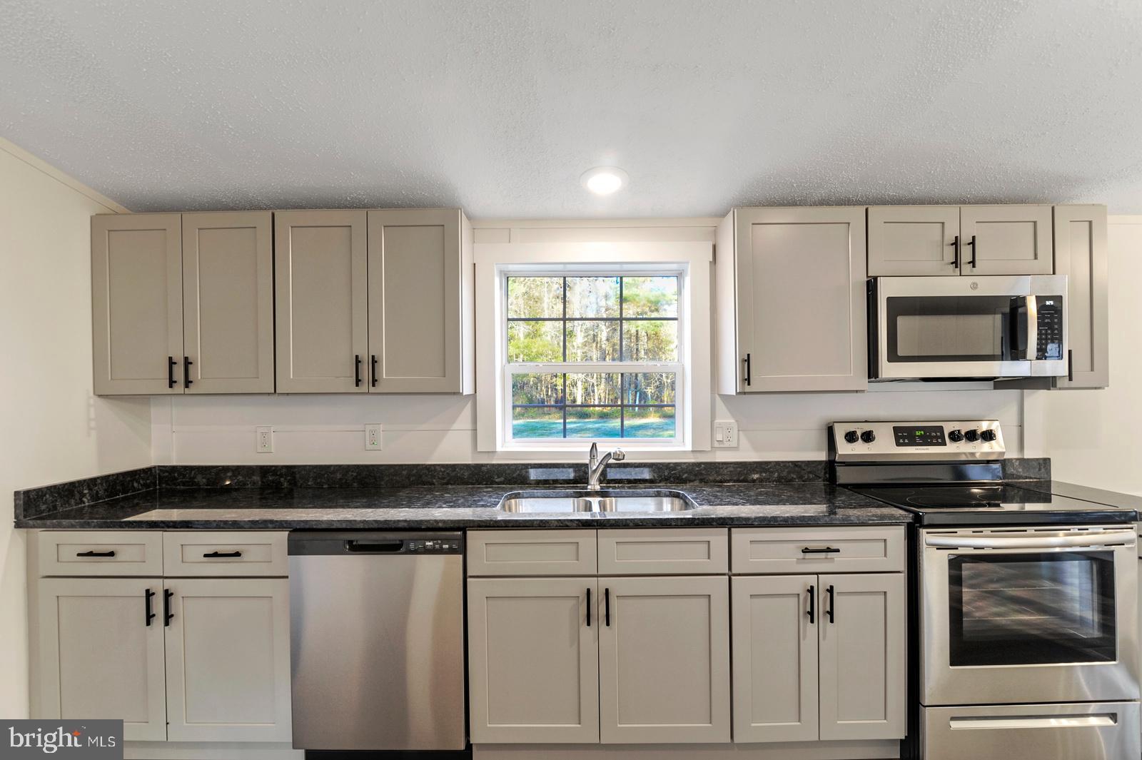 16745 Arvey Road Laurel, DE 19956 - Photo 22 of 35 a kitchen with granite countertop white cabinets sink and stainless steel appliances