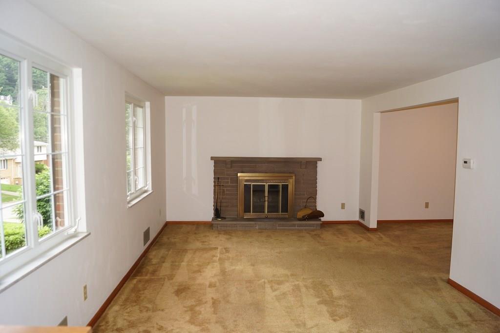 121 Kingsdale Road Pittsburgh, PA 15221 - Photo 4 of 25 Living room features a log burning fire place and plenty of natural light. Hardwood floors underneath the carpet.