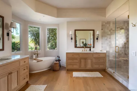 a bathroom with a double vanity sink a large mirror a bathtub and next to a window