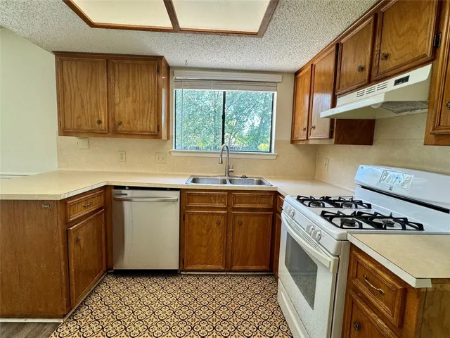 a kitchen with granite countertop a sink a stove and cabinets