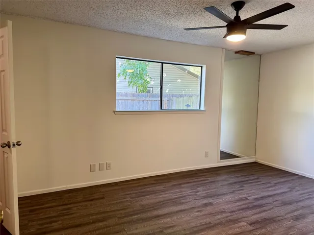 an empty room with wooden floor chandelier fan and windows
