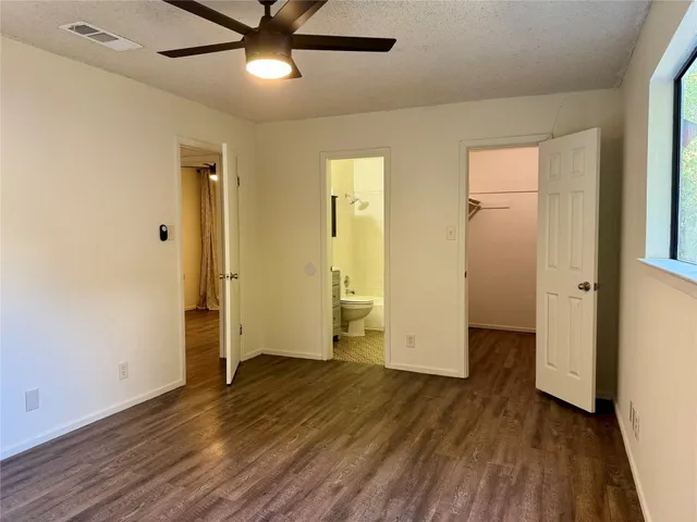 an empty room with wooden floor and a ceiling fan