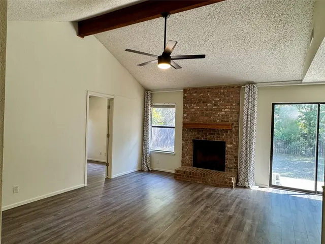 an empty room with wooden floor fireplace and windows