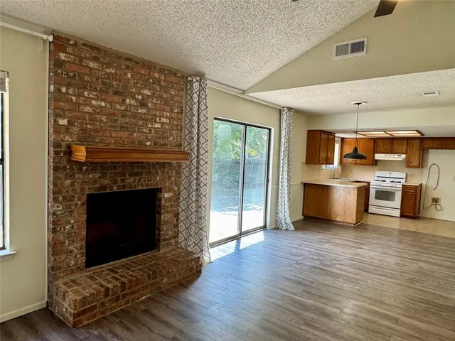 a living room with stainless steel appliances wooden floor and a fireplace