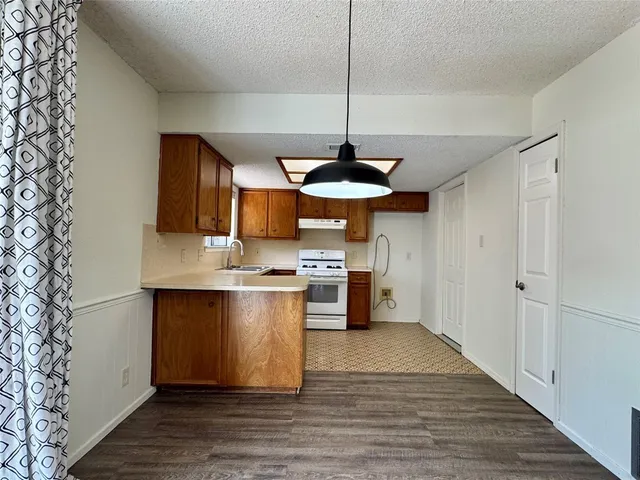 a kitchen with stainless steel appliances granite countertop a sink a stove and a wooden floors