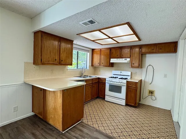 a kitchen with stainless steel appliances granite countertop a stove a sink and a microwave